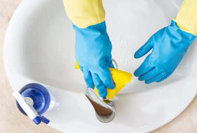 Hands with gloves cleaning a bathroom with a yellow rag. Disinfection or hygiene concept