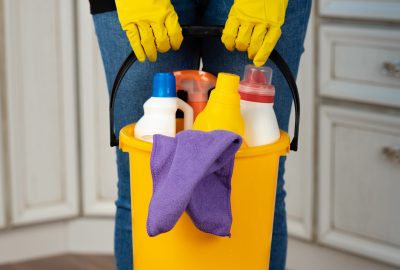 Woman holding a bucket with liquid detergents for house cleaning