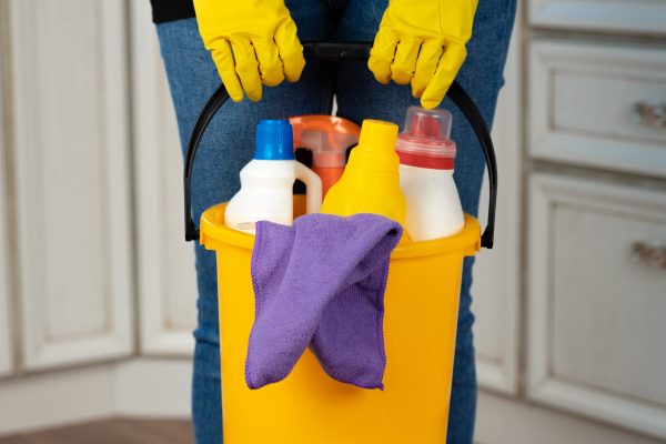 Woman holding a bucket with liquid detergents for house cleaning